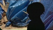 Silhouette of small child eating in refugee camp&sbquo;  blue tent in background&sbquo; Darfur; Nov 05