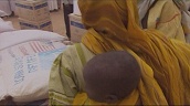 Sudanese woman lifts and carries food sack onto head whilst baby is strapped on back&sbquo;  El Geneina&sbquo; Sudan; Jun 06