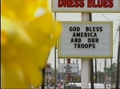 Pull focus on billboard with \%27God Bless America and Our Troops\%27 slogan across as yellow ribbon blows in wind&sbquo;  US; 27 Mar 03