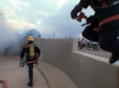 Firemen walk down into smoke filled underground car park carrying hoses
