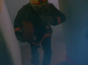 Firemen run up stairs through smoke carrying axe and rolled up fire hoses