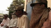 Tilt up from hands of former child Taliban soldiers as they sit lined with their faces covered&sbquo;  Pakistan; 3 August 2009