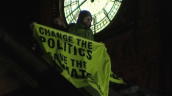Pan left from face of Big Ben to Greenpeace protestors holding banner on roof of Houses of Parliament at night&sbquo;  London; 12 October 2009