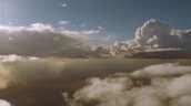 Track left past clouds lit up by streaming sunlight under blue sky