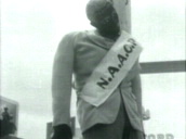 Effigy hanging from makeshift gallows depicting African-American member of National Association for the Advancement of Colored People; pan down to sign proclaiming "built by Union Labor"; Sep 56