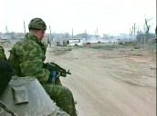 Russian solider holding AK-47 assault rifle&sbquo;  sitting on tank moving through debris strewn streets&sbquo; Grozny; 18 Feb 00