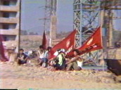 Construction workers sitting on rubble during break&sbquo;  red flags flap behind&sbquo; Pyongyang; 1988