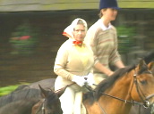 Queen Elizabeth II wearing head scarf horse riding with grooms&sbquo;  turns and frowns at camera&sbquo; Windsor grounds; Jun 94