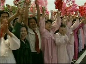 Track right across cheering crowds waving pink flowers following renewed relations between North and South Korea as President Kim Jong Il and President Kim Dae Jung arrive at Pyongyang airport&sbquo;  North